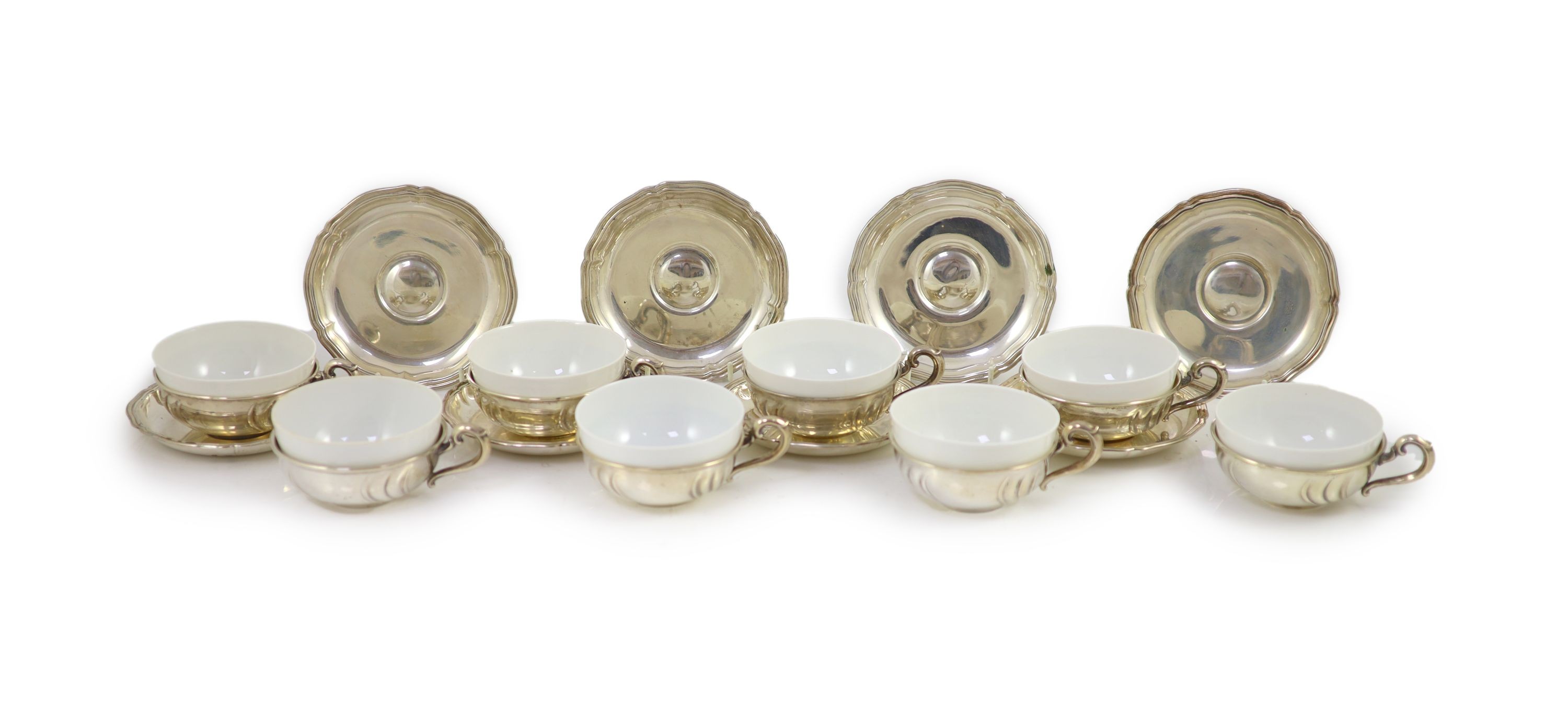 A set of eight German 800 standard silver cups and saucers, by Adolf Kander, with white porcelain liners
